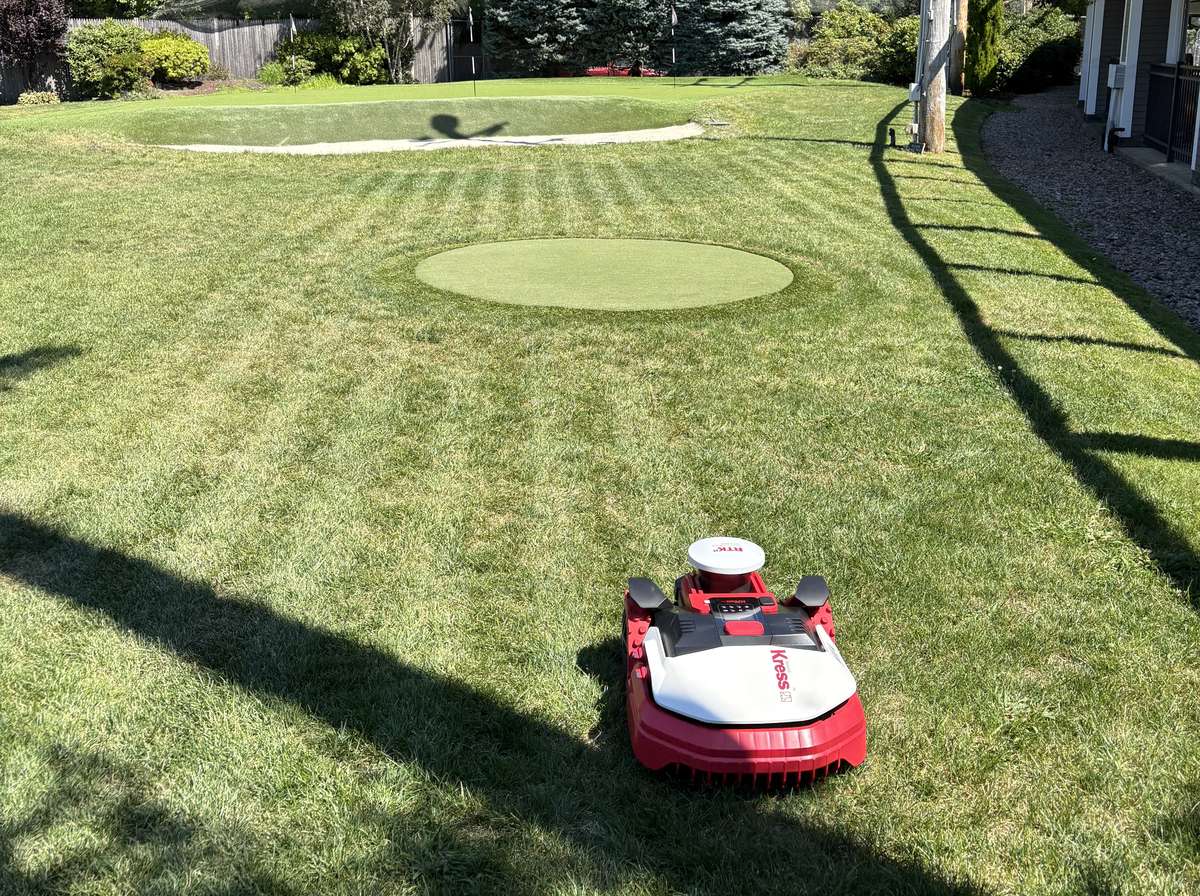 A Kress robot mowing beside a practice green